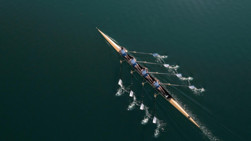 four people rowing a canoe in open water