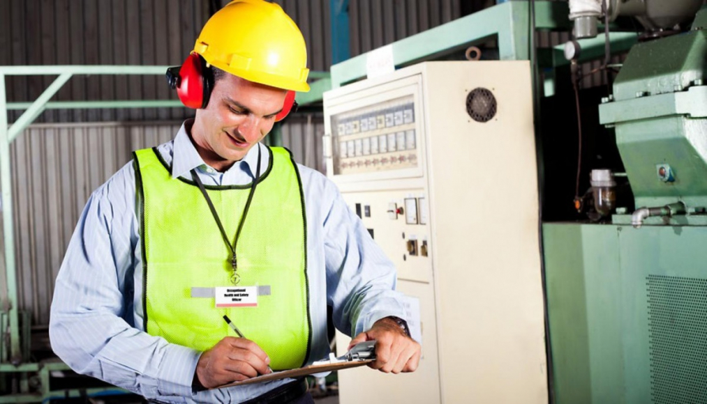 Man in safety gear writing on clipboard 
