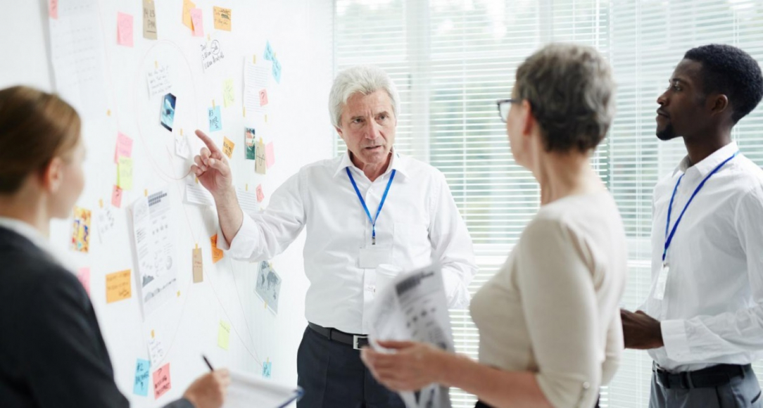 people discussing papers on a whiteboard 