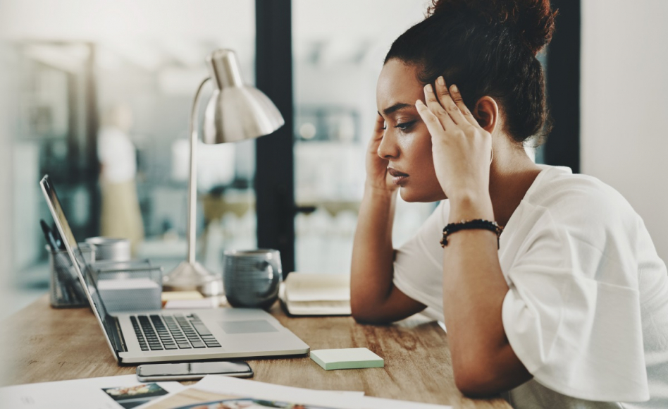 woman holding her head at desk
