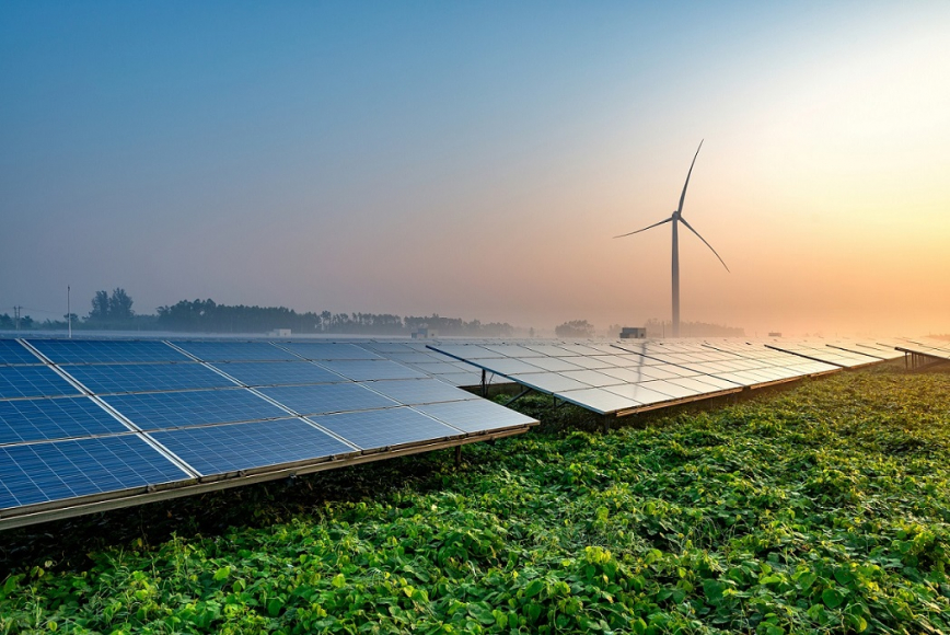 Windmill and solar panels in field 