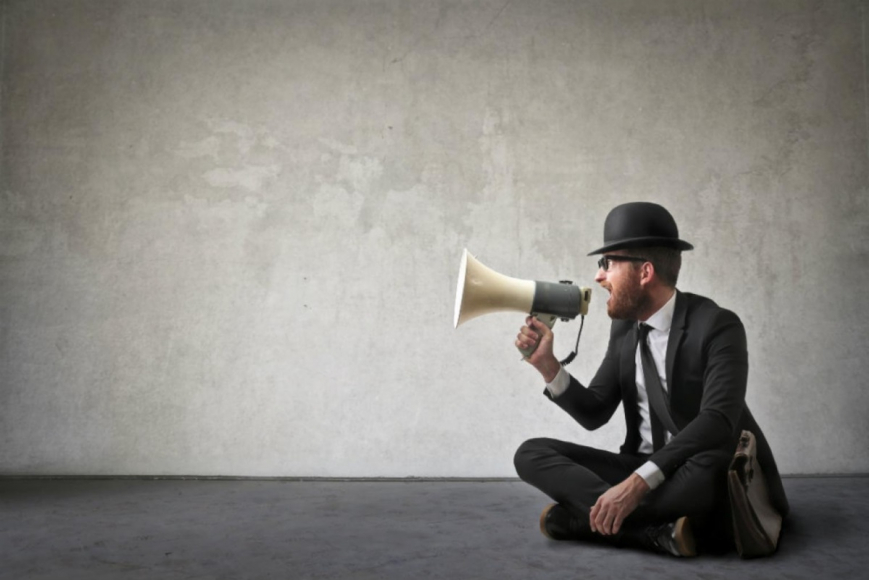 Man wearing a top hat taking into megaphone