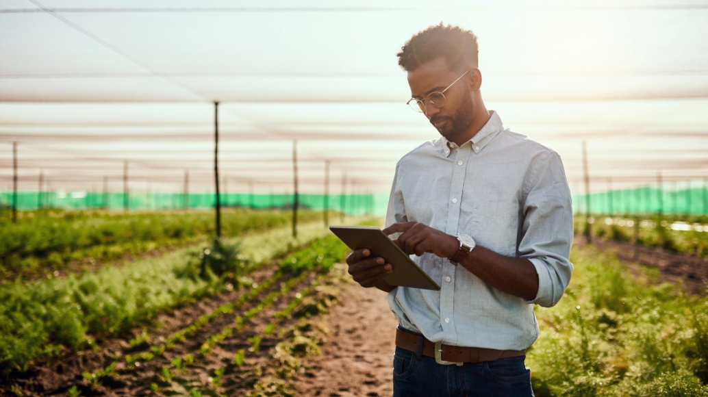 man in a suit in a sustainable farming field marking on iPad